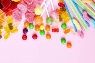 Renkli şeker ve meyve pembe bir arka plan üzerinde şekerlemeler