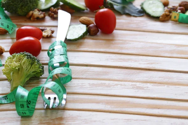 Conceito de dieta - garfo com fita métrica em uma mesa de madeira — Fotografia de Stock