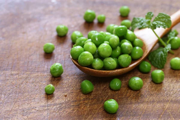 Verse groene erwten in een houten lepel — Stockfoto