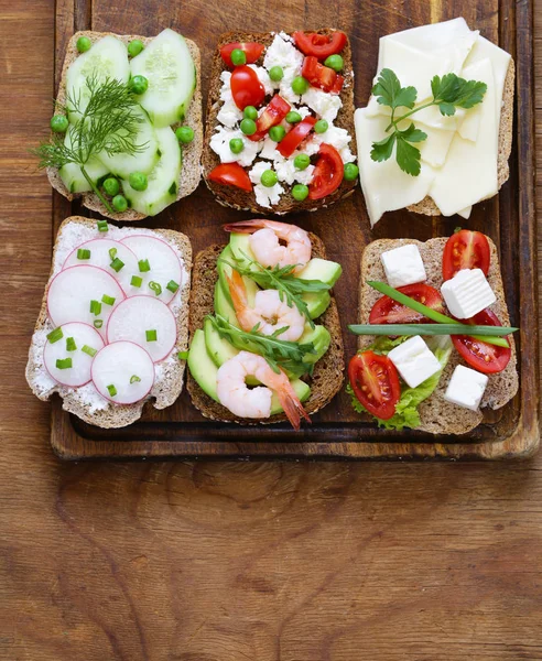 variety of sandwiches with different fillings (avocado, shrimp, fish, ham, vegetables)