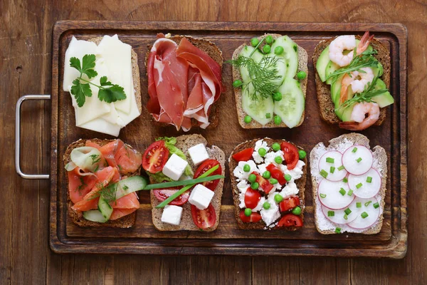 Varietate de sandvișuri cu umpluturi diferite (avocado, creveți, pește, șuncă, legume ) — Fotografie, imagine de stoc