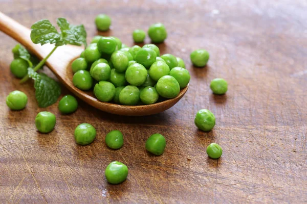 Verse groene erwten in een houten lepel — Stockfoto