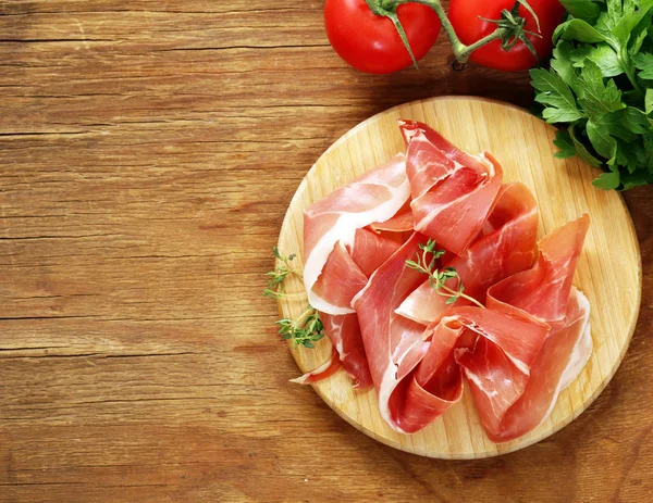 Smoked Parma ham on a wooden board — Stock Photo, Image