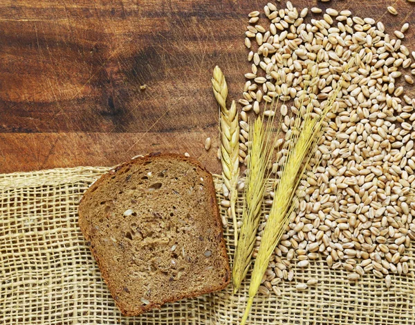 Fondo in legno con tela grezza e spighe e grani di grano — Foto Stock