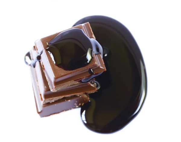 Stücke dunkler Schokolade und Sirup auf weißem Hintergrund — Stockfoto
