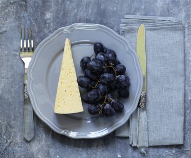 Dilim peynir ve bir fırça gri bir plaka üzerinde üzüm