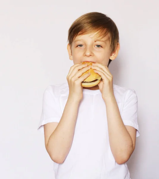 Schattige blonde jongen eten cheeseburger - Amerikaanse voedsel — Stockfoto