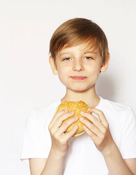 Schattige blonde jongen eten cheeseburger - Amerikaanse voedsel — Stockfoto