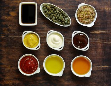 Different types of sauces and oils in bowls, top view clipart