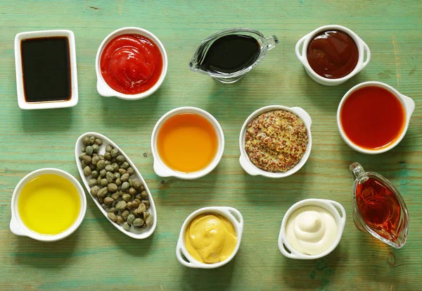 Различные типы соусов и масел в мисках, вид сверху — стоковое фото