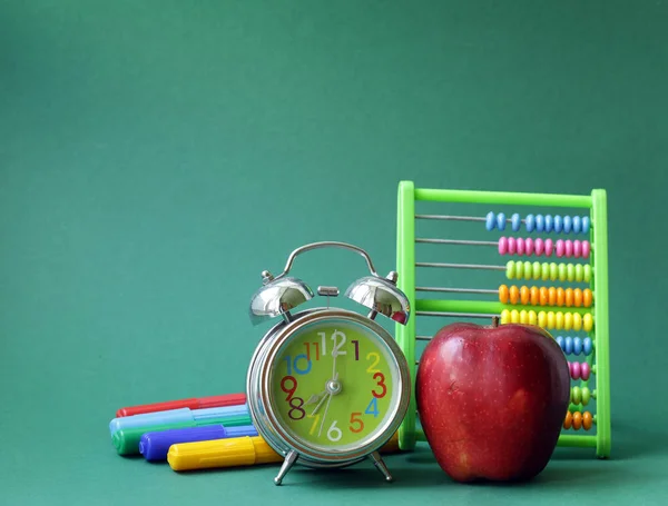 Fournitures scolaires et pomme sur fond vert — Photo