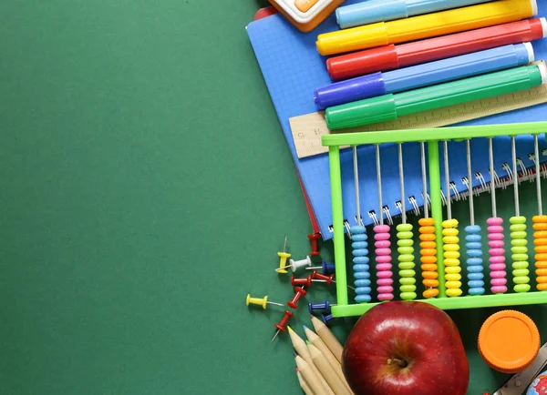 Fournitures scolaires et pomme sur fond vert — Photo