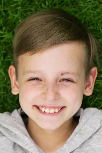 Schattige jonge jongen rusten op het groene gras - zomertijd, picknick — Stockfoto