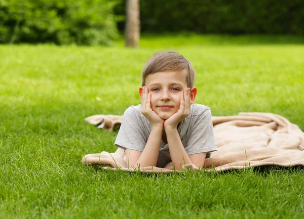 Mignon jeune garçon reposant sur l'herbe verte - heure d "été, pique-nique — Photo