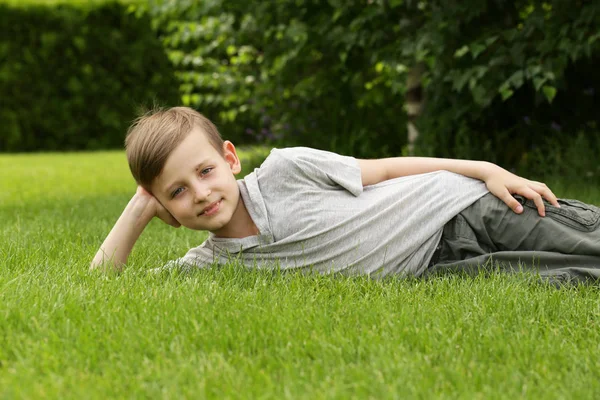 Милый мальчик отдыхает на зеленой траве - летнее время, пикник — стоковое фото