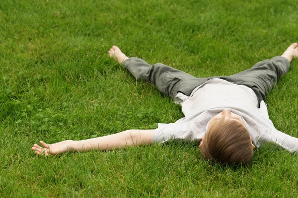 Cute young boy resting on the green grass - summer time, picnic — Stock Photo, Image