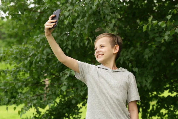 Carino biondo ragazzo facendo selfie in un parco all'aperto — Foto Stock