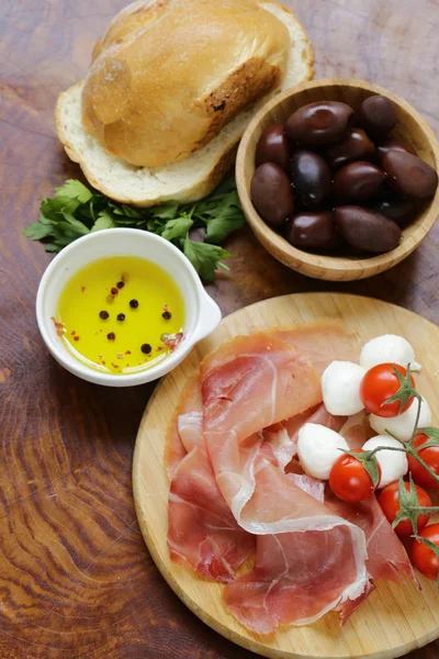 Итальянская кухня - оливки, ветчина парма, помидоры, сыр моцарелла — стоковое фото