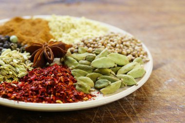 Ahşap arka plan üzerinde çeşitli baharatlar (kakule, kırmızı biber, kişniş, rezene)