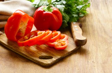 Ahşap masa üzerinde organik gıda tatlı kırmızı biber dilimlenmiş