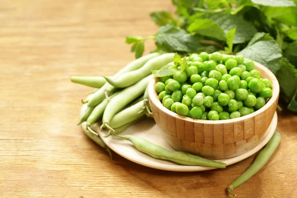 Färska gröna ärtor på ett träbord, ekologisk mat — Stockfoto