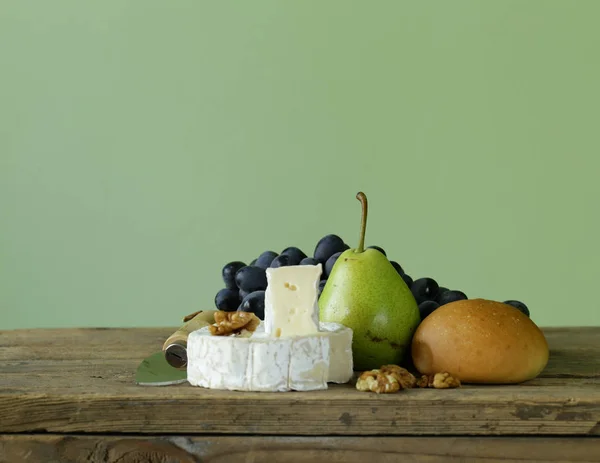 Camembert cheese with grapes on a wooden board — Stock Photo, Image