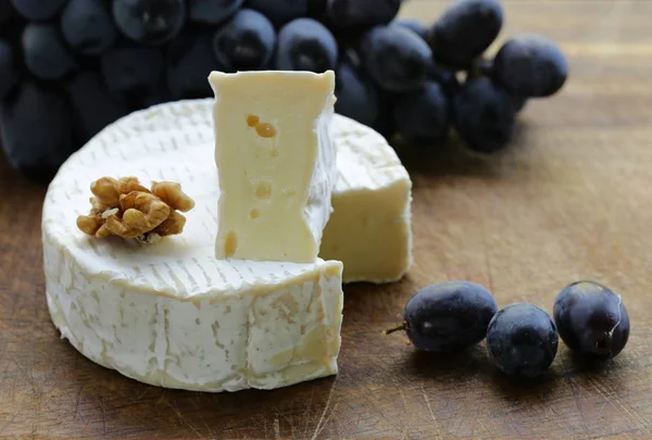 Camembert cheese with grapes on a wooden board — Stock Photo, Image