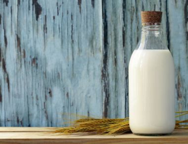 Ahşap bir masa üzerinde bir cam şişe içinde organik süt