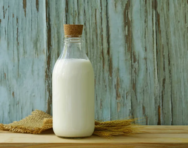 Ahşap bir masa üzerinde bir cam şişe içinde organik süt