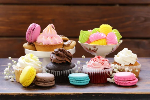 Десертный стол - кексы, печенье, макароны, кексы на деревянном фоне — стоковое фото