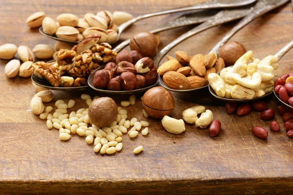 Différents types de noix (cèdre, noix de cajou, noisettes, noix) dans des cuillères — Photo