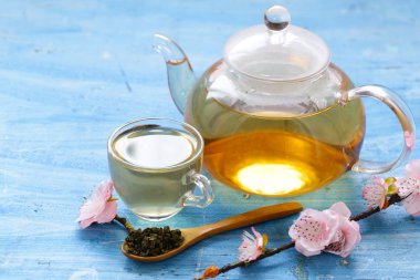 Bir çaydanlık kiraz çiçekleri bir dalı ile yeşil çay