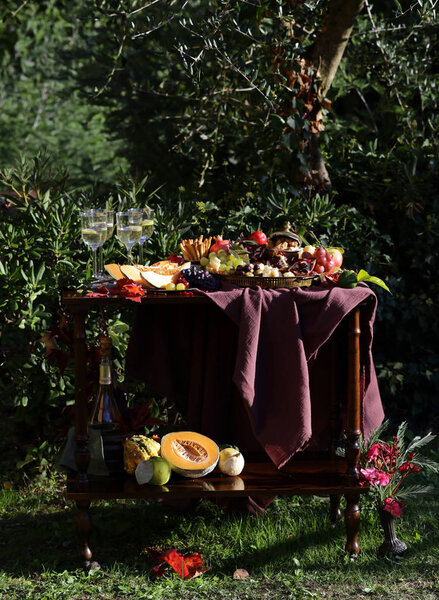 стол в саду с фруктами и вином
