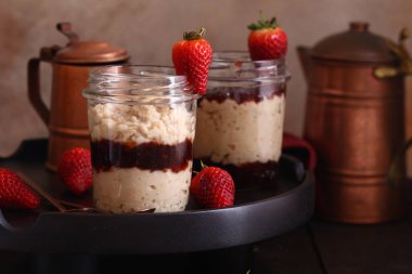 Kahvaltıda cam kavanozda çilek reçelli yulaf ezmesi.