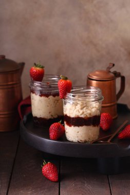 Kahvaltıda cam kavanozda çilek reçelli yulaf ezmesi.