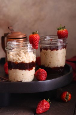 Kahvaltıda cam kavanozda çilek reçelli yulaf ezmesi.