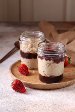 Kahvaltıda cam kavanozda çilek reçelli yulaf ezmesi.