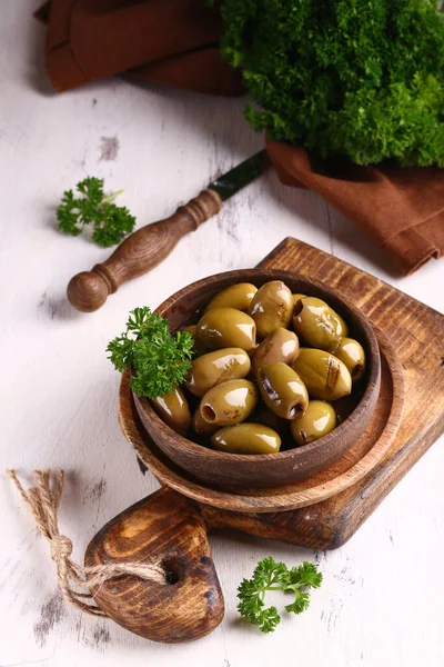 用木碗盛放在油中的绿色腌制橄榄 — 图库照片