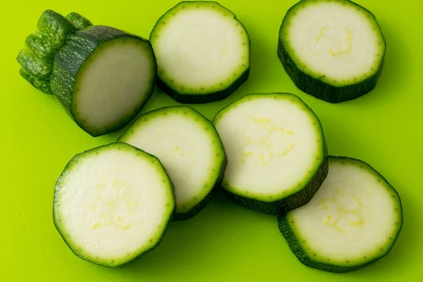 fresh green zucchini slices on green background