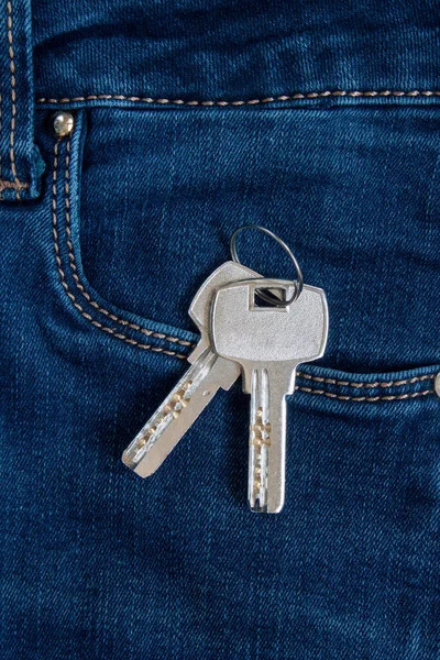キーチェーンの家への2つの鍵は青いジーンズのサイドポケットに横たわっています. — ストック写真