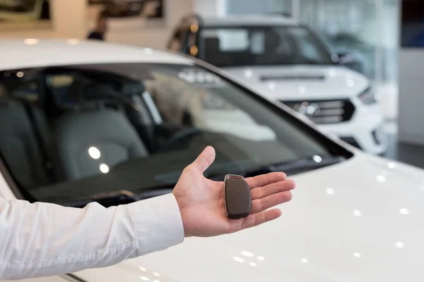 Der Händler hält die Schlüssel für ein neues Auto in der Hand. moderne und prestigeträchtige Fahrzeuge. — Stockfoto