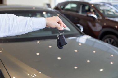 Yeni bir arabanın anahtarlarını tutan satıcı. Modern ve prestijli araçlar.