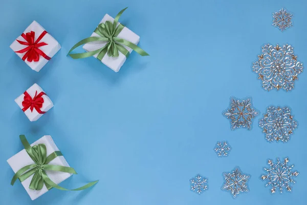 Julklappar och snöflingor isolerade på blå bakgrund. Kopiera utrymme för din text. — Stockfoto