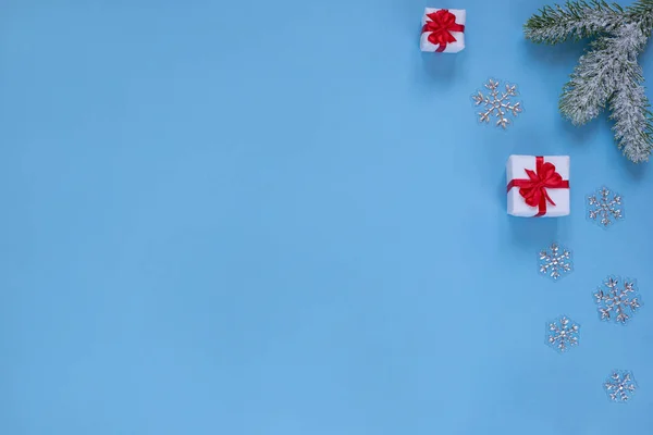 Julklappar, snöig kvist av tall och dekorativa snöflingor isolerade på blå bakgrund. Kopiera utrymme för din text. — Stockfoto