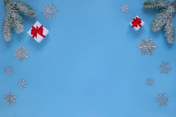 Julklappar med band, snöig kvist av tall och dekorativa snöflingor isolerad på blå bakgrund. — Stockfoto