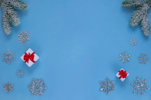 Julklappar med band, snöiga kvistar av tall och dekorativa snöflingor isolerade på blå bakgrund. Kopiera utrymme. — Stockfoto