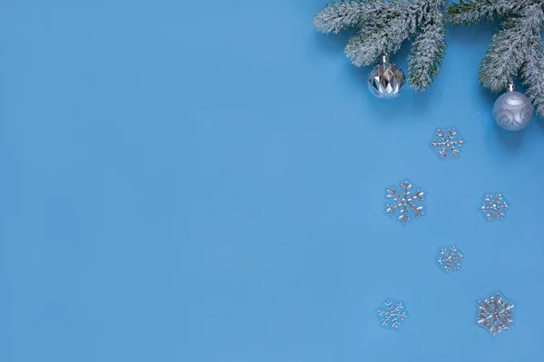 Raminhos nevados de pinho com bolas de Natal, flocos de neve isolados no fundo azul. Conceito de Natal e Ano Novo . — Fotografia de Stock