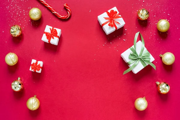 Bolas de crismas douradas, presentes de Natal e cana de caramelo isolada no fundo vermelho. Conceito de Natal e Ano Novo . — Fotografia de Stock