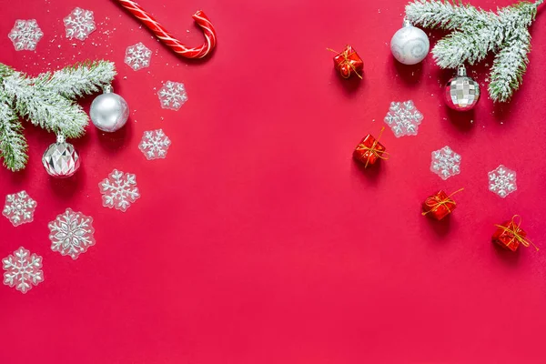 Snowy sprigs of pine, snowflakes, caramel cane, chrismas balls and gifts isolated on red background. — Stock Photo, Image