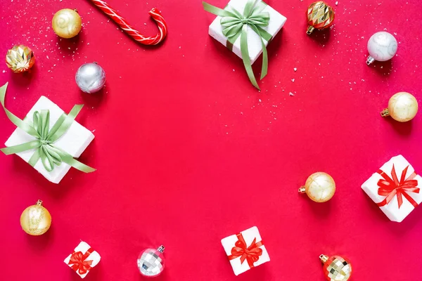 Рождественские шары, рождественские подарки и карамельный тростник выделены на красном фоне. Концепция Рождества и Нового года . — стоковое фото